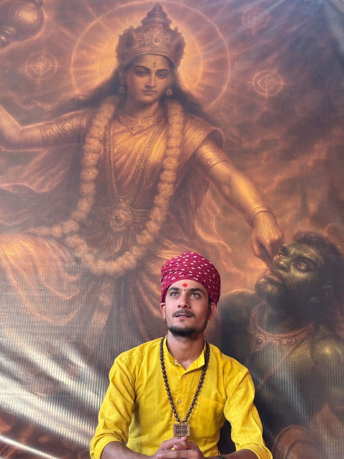 Aacharya Pandit Yogesh Sharma seated before an image of Maa Baglamukhi