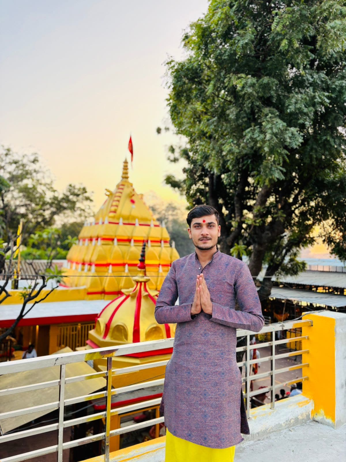 Aacharya Pandit Yogesh Sharma standing with folded hands before the Maa Baglamukhi Temple shikhar at Nalkheda